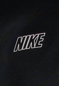 Černá tkanina s logem "NIKE" v tučném bílém písmu s tenkým obrysem, umístěným výrazně uprostřed.