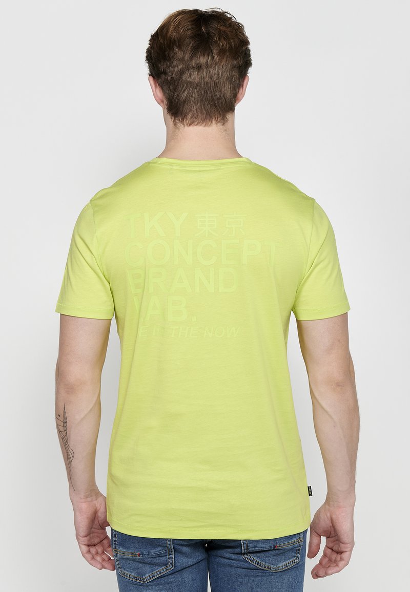 Limegrön t-shirt med kort ärm som har en stor, tonad texttryck på baksidan. Tillverkad av mjukt material med en avslappnad passform.