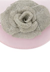 Vaaleanpunainen kangashattu, jossa on kiiltävä hopeinen rhinestone-kukkaaksentti edessä, ominaisuutenaan sileä pinta ja pyöreä muoto.