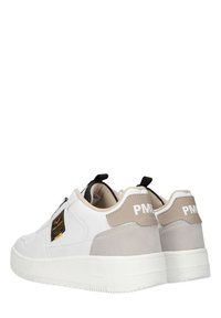 Baskets blanches avec une tige en cuir lisse, des accents en daim beige, des détails noirs et une semelle blanche épaisse. Marque visible sur le talon.