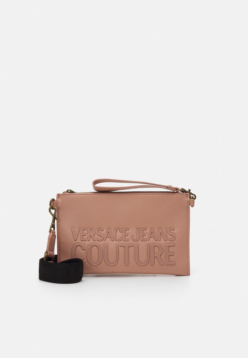 Růžová syntetická kabelka typu clutch se zvýrazněným textem "VERSACE JEANS COUTURE", zipovým uzávěrem, odnímatelným popruhem a hladkým povrchem.