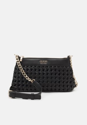 Zwarte geweven crossbodytas met gouden kettingriem en "GUESS EST 1981"-logo in gouden letters op het gladde bovenpaneel.