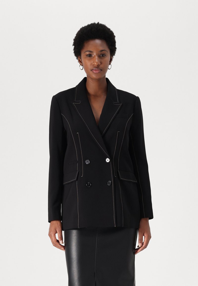 Blazer doppiopetto nero con cuciture beige a contrasto, rever strutturato, due tasche frontali e due grandi bottoni.