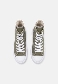Zapatillas de lona color caqui de caña alta, con cordones blancos, punteras redondas y suelas de goma con una textura suave.