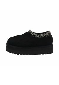 Zapatos de ante negro tipo slip-on con un detalle de costura texturizada alrededor del cuello y una suela gruesa y duradera con un patrón de zigzag.