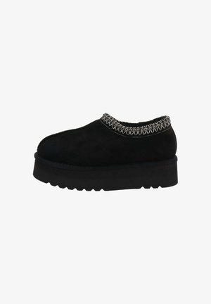 Zapatos de ante negro tipo slip-on con un detalle de costura texturizada alrededor del cuello y una suela gruesa y duradera con un patrón de zigzag.