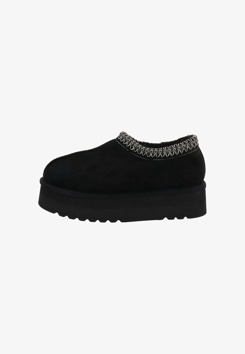 Zapatos de ante negro tipo slip-on con un detalle de costura texturizada alrededor del cuello y una suela gruesa y duradera con un patrón de zigzag.