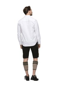 White long-sleeve shirt, black shorts, and knit leg warmers with a patterned design. Black footwear completes the outfit.