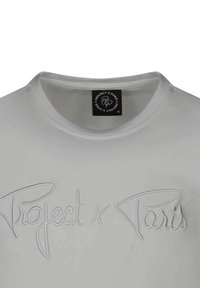 Camiseta blanca de algodón con cuello redondo y logotipo en relieve "Project x Paris" en una fuente cursiva en la parte frontal.