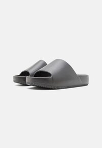 Sorte åpne sandaler med en glatt, matt tekstur og et avrundet, minimalistisk design. Sålen har riller for grep.