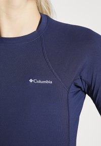 Sötétkék hosszúujjú póló sima anyagból, lapos varrással, fehér "Columbia" logóval a mellkasán.