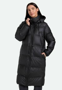 Cappotto lungo imbottito nero con colletto alto, cappuccio regolabile con cordino, zip frontale e tasche laterali. Texture liscia e lucida con cuciture orizzontali.