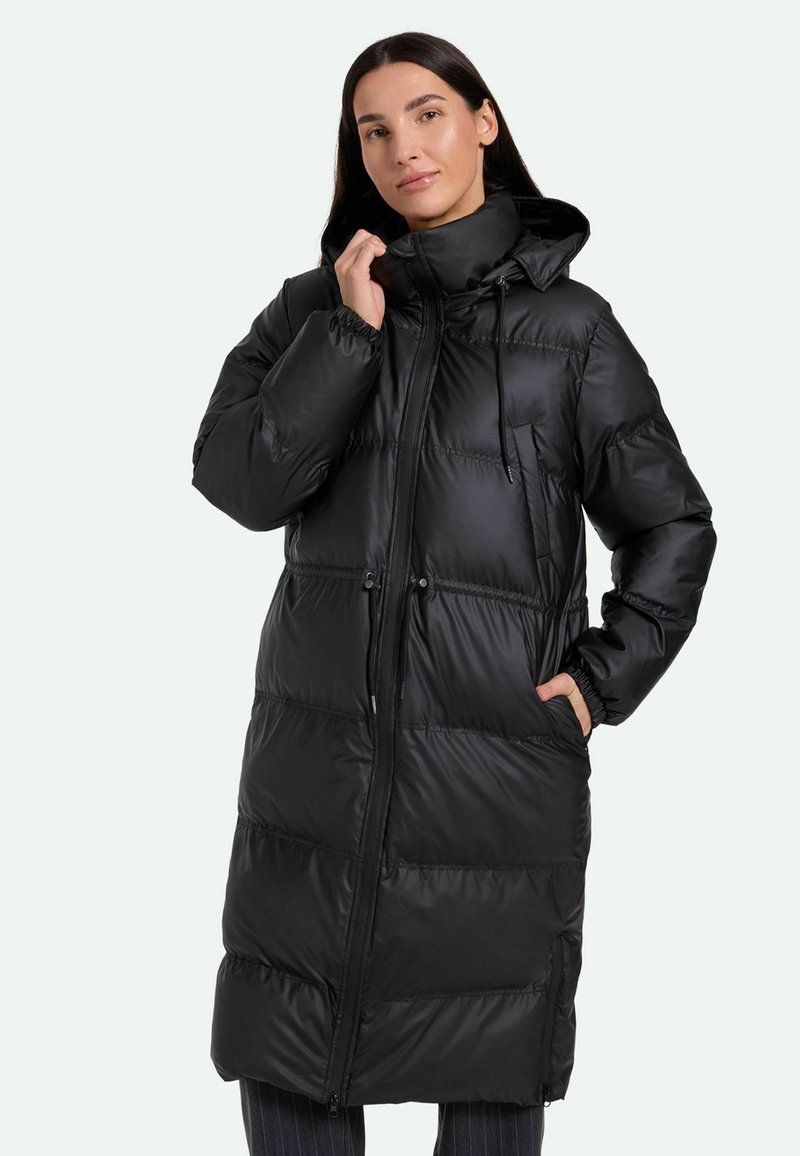 Cappotto lungo imbottito nero con colletto alto, cappuccio regolabile con cordino, zip frontale e tasche laterali. Texture liscia e lucida con cuciture orizzontali.