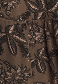Tejido marrón con un patrón floral en negro y beige. Presenta hojas y flores, con una superficie texturizada y detalles recogidos.