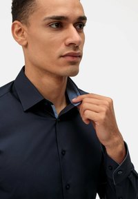 Marineblauwe overhemdd met lichtblauwe accenten op de kraag en manchetten, met een gladde textuur en een knoopsluiting.