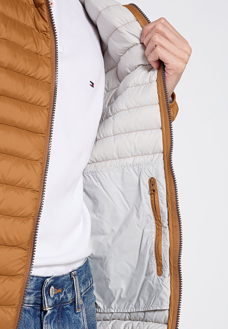 Giacca a vento marrone con esterno trapuntato, interno grigio a contrasto e tasca laterale con zip. Dotata di una robusta cerniera metallica.