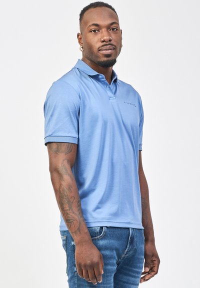 Polo shirt azzurro con colletto, maniche corte e un piccolo logo sul petto. Indossato con jeans in denim blu. Texture liscia.