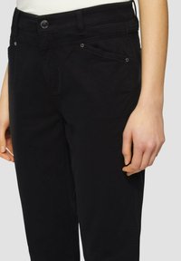 Pantalons en coton noirs avec une coupe slim, dotés de poches avant, de subtils détails de couture et d'une fermeture à un bouton à la taille.