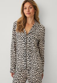 Panterprint natbukser i blødt stof; har lange ærmer, skjortekrave, knaplukning foran og en enkelt brystlomme.