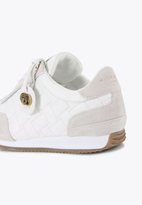 Sneaker bianco con design in pelle intrecciata e dettagli in suede, caratterizzato da una piccola rifinitura in oro e una suola in gomma testurizzata.