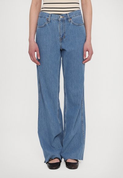 Light blue wide-leg denim jeans with a high waist, five-pocket design, and faded texture, paired with black flats.