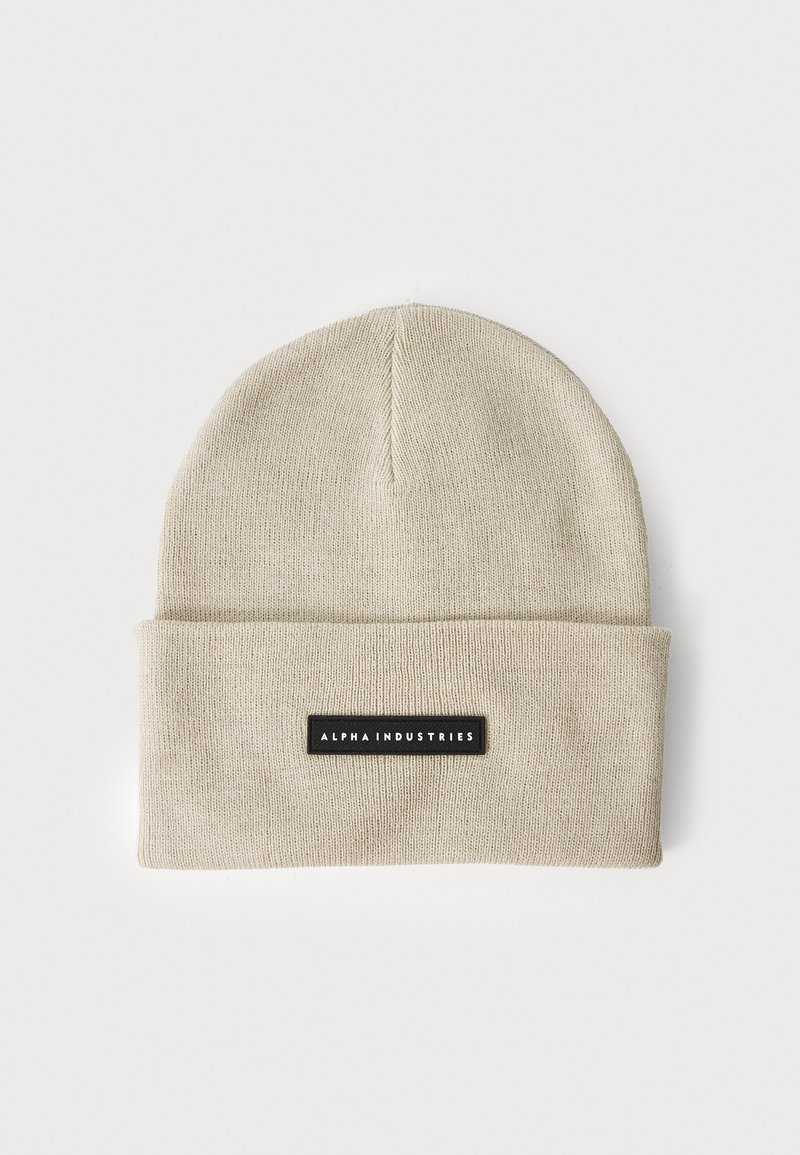 Gorro de malha bege com dobra na bainha e um rótulo preto. Apresenta uma textura suave e um design simples. Adequado para uso casual.