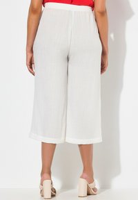 Culottes en lin blanc avec un design à jambes larges, dotées d'une taille froncée et d'une longueur courte. Texture lisse et finition unie.