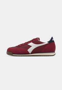 Red suede and mesh athletic shoes with white accents and a navy heel. Features a rounded toe and textured rubber sole.