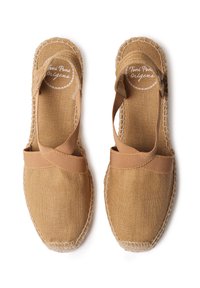 Hnědé espadrilky s plátěným svrškem a elastickými pásky. Mají tkané jutové podešve a kontrastní prošití podél okrajů.
