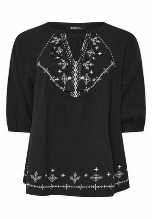 Blusa nera con texture, caratterizzata da motivi floreali ricamati bianchi e un collo con fiocco. Maniche a tre quarti e dettagli di cucitura decorativa.