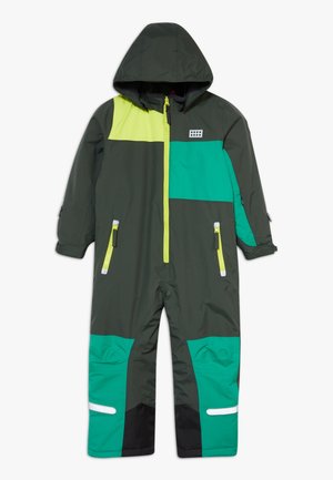 Wasserdichter Einteiler in Dunkelgrün mit gelben und türkisfarbenen Bereichen, mit durchgehendem Reißverschluss, Kapuze und reflektierenden Akzenten an den Taschen und unten.