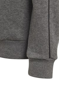 Polsino di felpa grigia con tessuto morbido, texture a costine e finitura pulita con un sottile accento nero sulla cucitura.