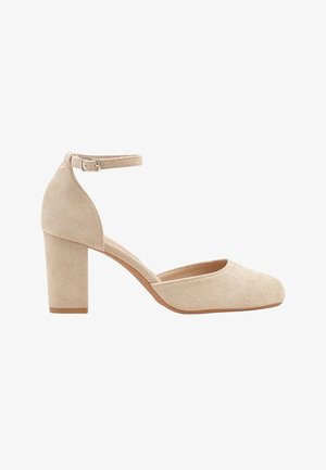 Escarpin pour femme en daim beige avec talon bloc, bout arrondi fermé et bride de cheville avec boucle sur fond blanc.