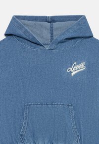 Blå denimhuva med textur, framficka och vit broderad "Levi's"-logotyp på bröstet under huvan.