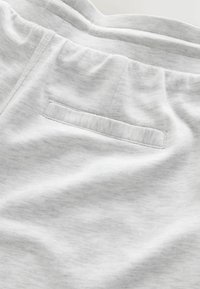 Light gray sweatpants made of soft fabric, featuring a smooth texture, elastic waistband, and a flat pocket on the back.
