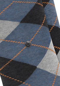 Chaussettes tricotées arborant un motif argyle bleu, gris et noir, avec des coutures orange contrastantes et un accent en métal rond de marque.