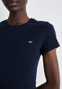 T-shirt di cotone blu navy con colletto tondo e maniche corte. Presenta un piccolo dettaglio del logo ricamato sul petto in rosso e bianco.