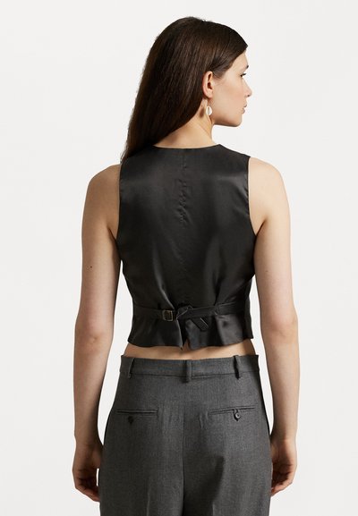 Top scurt din satin negru, cu un decolteu înalt și detalii cu legare la spate. Purtat cu pantaloni gri cu talie înaltă, dotati cu buzunare pe spate.