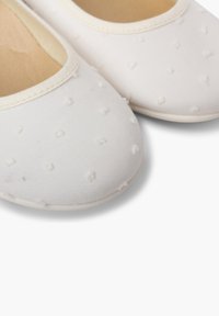 Ballerine bianche in tessuto con motivo a pois testurizzati, punta arrotondata e bordi elasticizzati per il comfort. Fodera interna liscia.