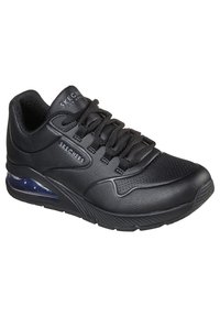 Des baskets Skechers noires présentent une tige en synthétique texturé, un design à lacets et une semelle avec coussin d'air visible. Branding minimaliste sur le côté.