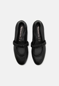 Une paire de chaussures Mary Jane en cuir noir avec des sangles élastiques froncées et un bout rond, taille 37, vue de dessus sur fond blanc.