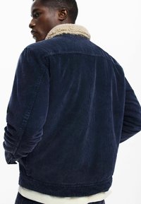 Nautička kotirana jakna s pješčanim krznom ovratnikom, opuštenog kroja i rebrastom teksturom. Vidljivi šavovi i standardni manšeti.