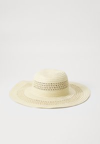 Sombrero de paja de ala ancha en color beige claro, con un diseño texturizado tejido y acentos calados cerca de la corona.