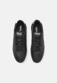 Schwarze Sneakers mit einem glatten Leder-Obermaterial, perforierter Zehenpartie, Textilfutter, flachen Schnürsenkeln und einer weißen Gummisohle. Das Logo "REPLAY" ist sichtbar.