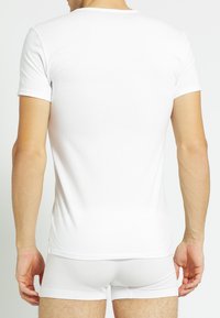 White short-sleeve t-shirt shown from the back, made of soft fabric, featuring a crew neckline and a fitted silhouette.