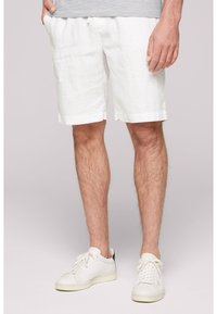 Shorts en lin blanc à coupe décontractée, avec une taille à cordon et un ourlet retroussé, associés à des baskets blanches.