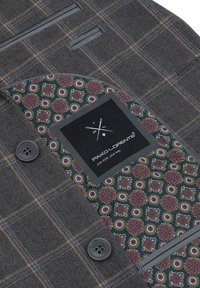 Veste à carreaux grise avec des boutons foncés, montrant une doublure intérieure colorée à motif floral et une étiquette noire indiquant « Pako Lorente ».