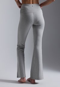 Gray flared yoga pants made of soft, stretchable fabric. Features a ruched high waistband and a smooth texture, with no visible patterns.