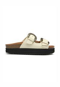 Cream-colored slide sandal with two adjustable buckles, a cork footbed, and a black rubber sole featuring a textured surface.