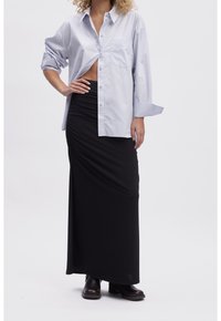 Light blue button-up shirt with rolled sleeves, paired with a long black ruched skirt. Model wears black ankle boots. Simple, clean design.